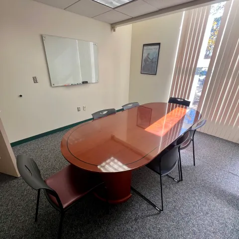 Large Study room with oval table a few chairs and white board on the wall. 